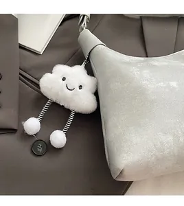 Chic white plush cloud keychain charm with smiley face on a stylish gray shoulder bag
