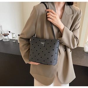 Détail du sac seau en toile gris foncé à pois avec un petit nœud argenté sur la bandoulière