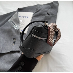 Detail of black pebbled leather handbag featuring a stylish silk scarf handle wrap