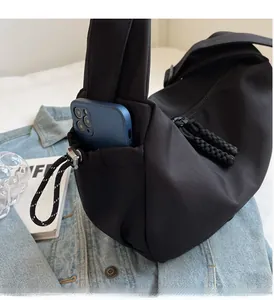 Détail du sac bandoulière en nylon noir avec poche latérale pour grands téléphones portables