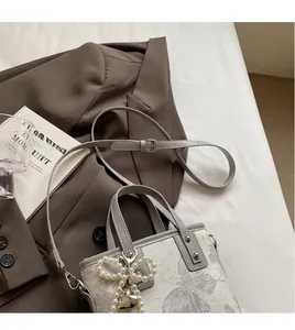 Detail of fabric bucket bag with pearl bow, heart charm and adjustable grey strap