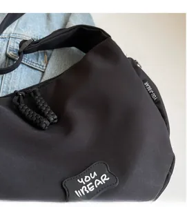 Détail du sac en toile noire avec fermeture éclair en corde tressée et patch de logo