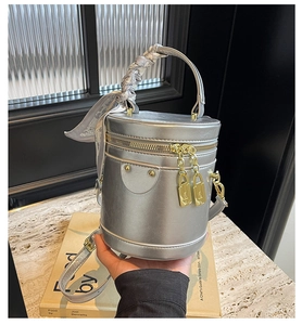 Detail of silver cylindrical handbag with silk scarf handle and golden padlock zippers