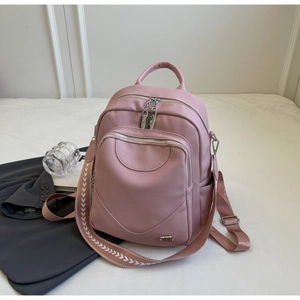 Détail d'un sac à dos rose en cuir souple avec grain litchi et bandoulière géométrique