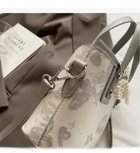 Close-up of white jacquard bucket bag with silver hardware and pearl pendant detail