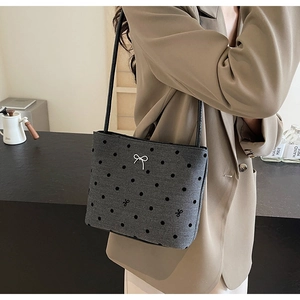 Gros plan du sac à bandoulière gris à pois en toile avec nœud argenté et lanière