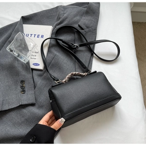 Macro detail of black lychee grain leather handbag with decorative scarf on the handle