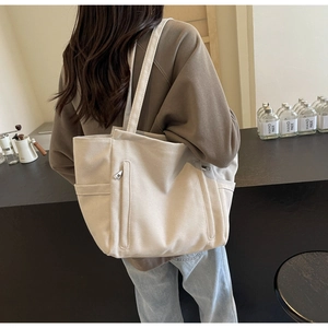Close-up of beige canvas tote bag showing the side zipper pocket and durable thick material