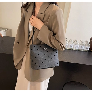 Détail du sac seau en feutre gris à pois noirs avec décoration de nœud argenté