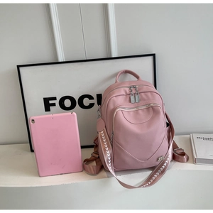 Détail du sac à dos en cuir rose avec poches zippées et bretelles à motifs géométriques