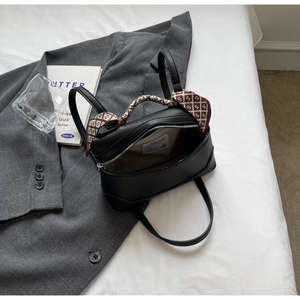 Detail of black lychee leather handbag with silk scarf handle and interior brand label