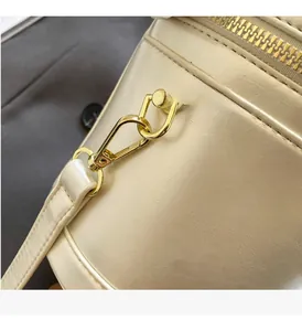 Close-up of golden metal hardware and zipper on creamy textured leather bucket bag