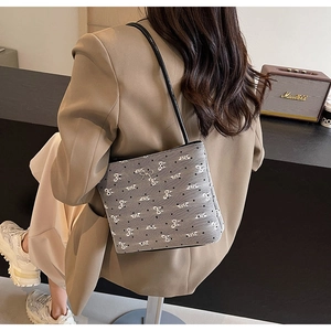 Détail d'un sac en toile gris à motifs de nœuds porté par un mannequin en style décontracté