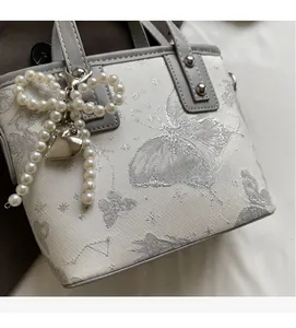 Detail of jacquard bucket bag with butterfly pattern and faux pearl bow charm