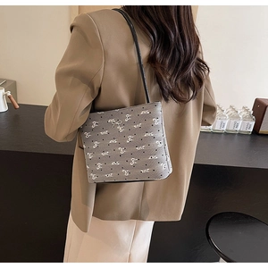 Détail du sac seau en toile grise avec motifs de nœuds blancs et petits points noirs