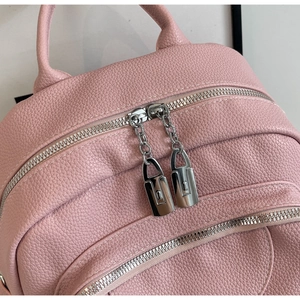 Détail du sac à dos en cuir rose avec fermetures éclair et pendentifs rectangulaires