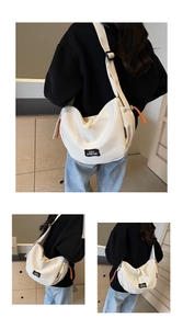 Détail du sac bandoulière en toile blanche avec fermeture orange et écusson de marque