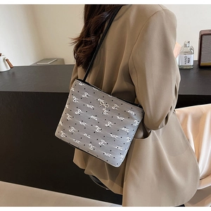 Détail du sac seau en toile grise avec broderie de nœuds blancs et pois noirs