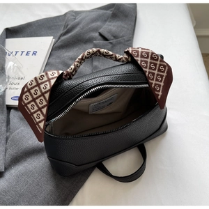 Detail of black lychee grain leather handbag with silk scarf handle and inner pocket