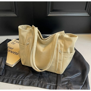 Detail shot of khaki canvas tote bag featuring a practical front zipper pocket and side slots