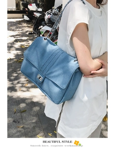 Détail du sac à bandoulière en denim bleu avec chaîne argentée et boucle métallique