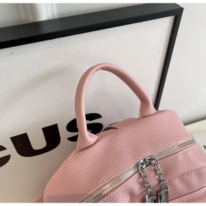 Détail d'un sac à dos en cuir rose avec fermetures éclair et cadenas décoratif argent
