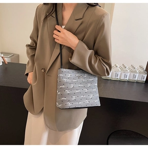Détail du sac seau en toile grise avec motifs de nœuds blancs et boucle métallique