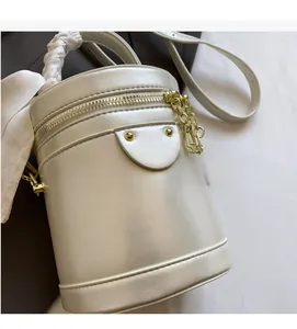 Detailed close-up of pearl white bucket bag with gold zipper and silk scarf handle