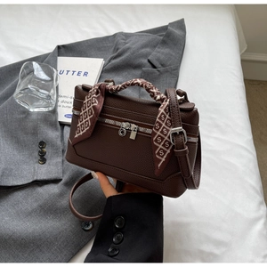 Detail of dark brown pebble leather handbag with silver zipper and decorative silk scarf