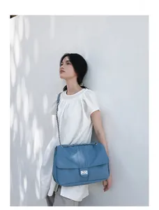 Gros plan du grand sac en denim avec fermoir tournant en métal argenté et bandoulière
