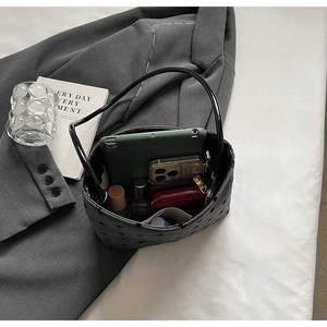 Intérieur spacieux du sac seau à pois noirs contenant tablette, téléphone et parfum