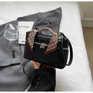 Detail of black pebbled leather vanity bag with a brown S-print silk scarf handle
