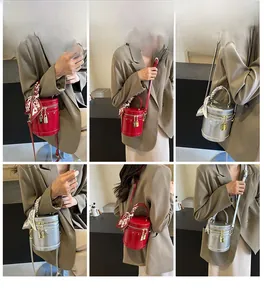 Detailed view of cylindrical metallic bucket bag with printed silk scarf on the handle