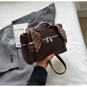 Close-up of brown lychee grain leather handbag with silk scarf detail and silver hardware