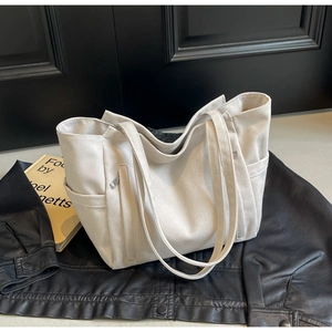 Close-up of cream canvas tote bag showing vertical zipper pocket and side compartments