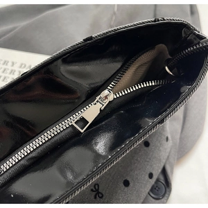 Détail de la fermeture argentée et cuir noir sur le sac seau en toile à pois gris