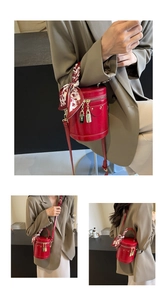 Detail of red cylindrical bucket bag with silk scarf handle and golden lock charms