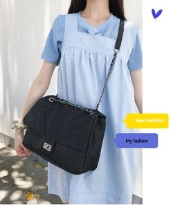 Détail du sac à rabat en denim noir avec fermoir rotatif argenté et bandoulière chaîne