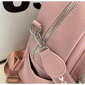 Gros plan sur cuir rose grainé avec zip argenté et bandoulière aux motifs cœurs