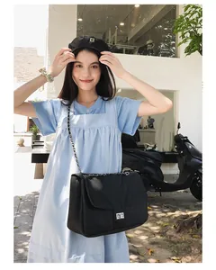 Gros plan du sac en denim noir avec chaîne argentée porté par un mannequin en ville