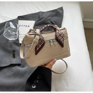 Close-up of cream beige Boston bag with lychee texture and silk scarf handle detail