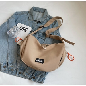 Détail du sac bandoulière en nylon beige avec fermeture éclair en corde orange vif