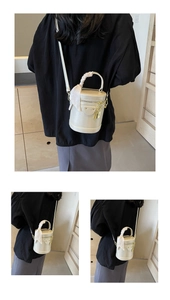 Detail of cream white cylinder bucket bag with a silk scarf wrapped around the handle