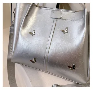 Close-up of metallic silver tote bag with 3D metal butterflies and fashion strap