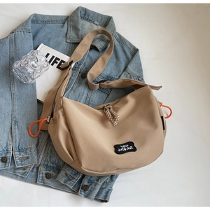 Détail du sac en toile kaki montrant l'écusson de marque et les accents orange vifs