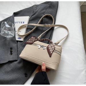 Close-up of beige lychee texture box bag with silver hardware and silk scarf handle detail