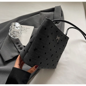 Détail d'un sac à main gris avec des pois noirs et un petit nœud métallique