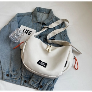 Détail du sac en toile blanc cassé avec cordes orange sur une veste en jean