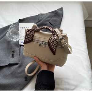 Close-up of beige lychee texture handbag with decorative silk scarf on handle