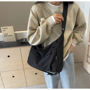 Detail of black canvas crescent bag with wide nylon strap and SHUNUO brand label